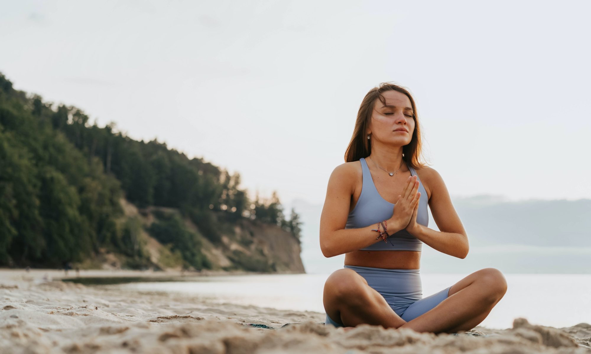 woman sitting on the beach doing a yoga posture