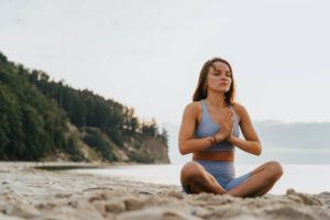 woman sitting on the beach doing a yoga posture
