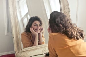 Woman Smiling and Looking at the Mirror